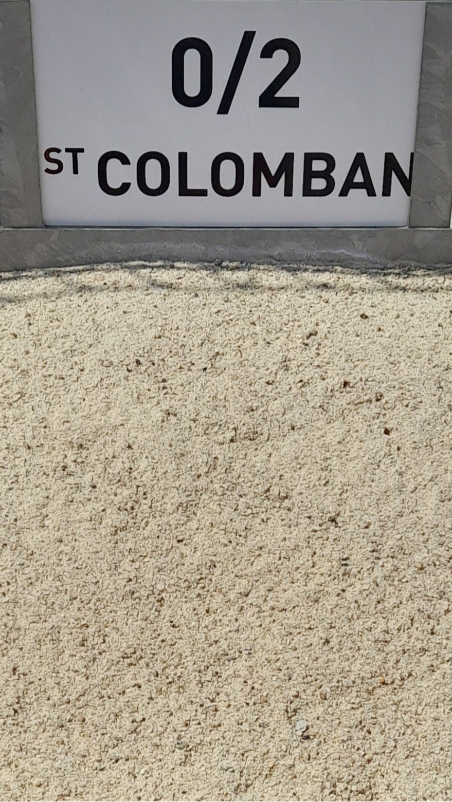 Tas de sable fin avec un panneau affichant "0/2 St Colomban" en fond, indiquant le type et la provenance du matériau.