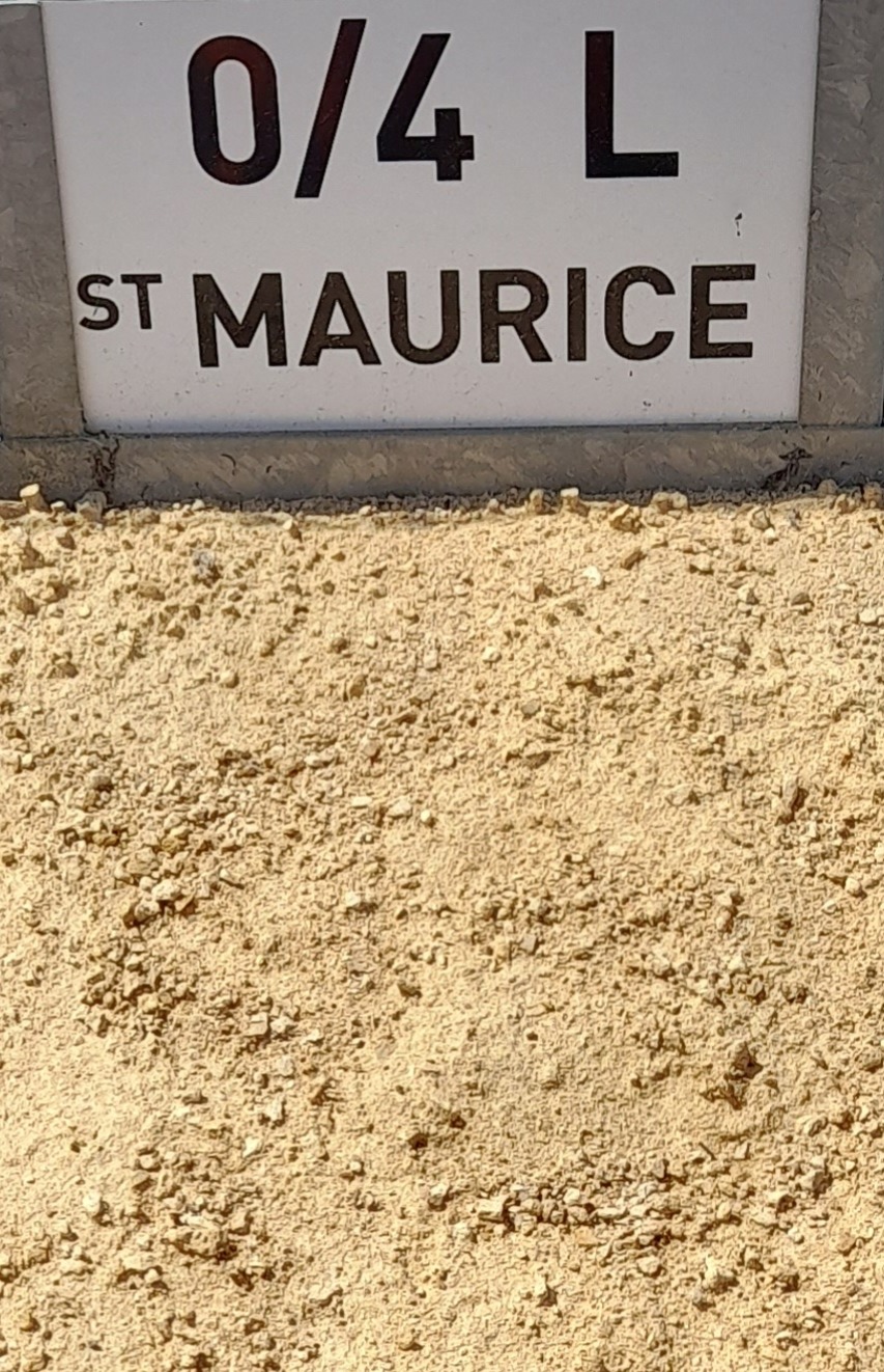 Plaque blanche avec l'inscription "0/4 L St Maurice" au-dessus d'un sol en sable jaune granulé, indiquant un tas de granulats de calibre 0/4 en provenance de Saint-Maurice.