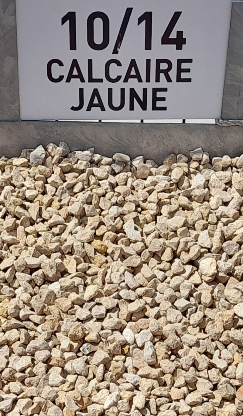 Gravillons de calcaire jaune de granulométrie 10/14 mm, présentés en gros plan avec un panneau descriptif en arrière-plan.
