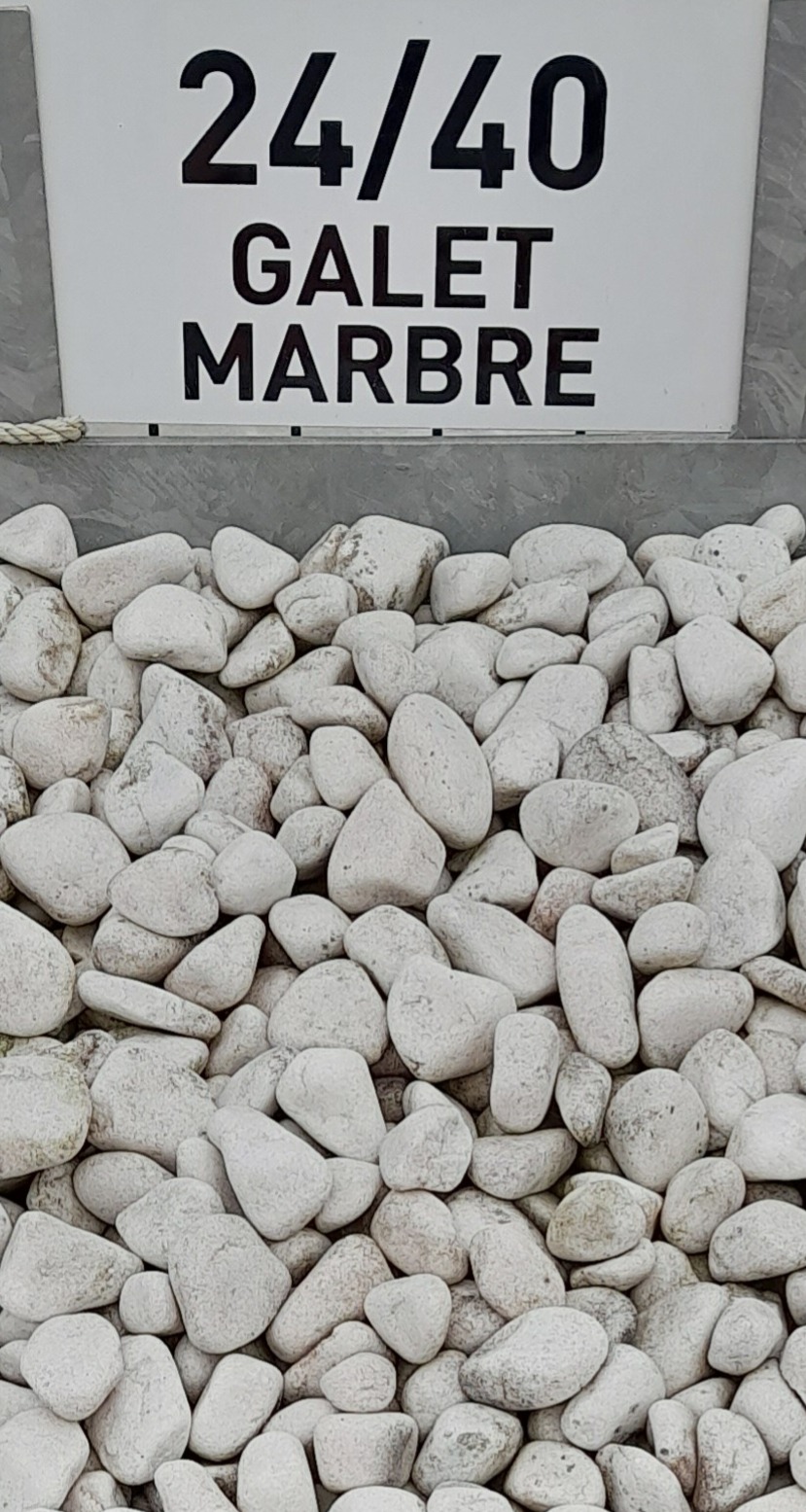 Galets de marbre blancs de taille 24/40 mm exposés sous un panneau indiquant "24/40 GALET MARBRE". Les galets sont de forme arrondie et uniformément répartis.