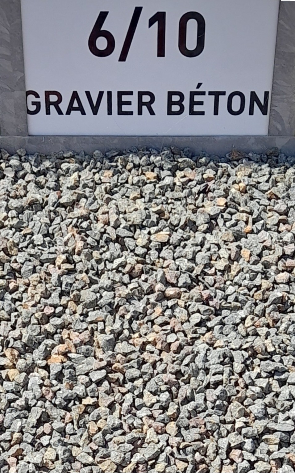 Gravier gris de calibre 6/10 visible en gros plan, avec un panneau en arrière-plan indiquant "6/10 GRAVIER BÉTON".