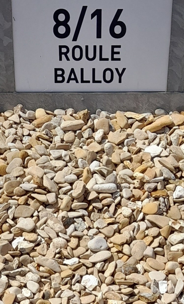 Gravier beige et blanc de taille 8/16 mm, étiqueté sur une pancarte blanche indiquant "8/16 ROULE BALLOY" en noir, avec un fond gris clair.