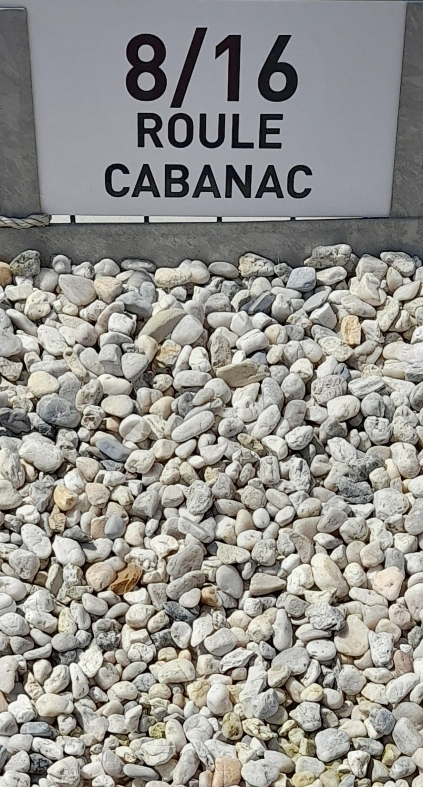 Tas de graviers blancs et beige étiqueté "8/16 ROULE CABANAC", utilisé pour les aménagements extérieurs.